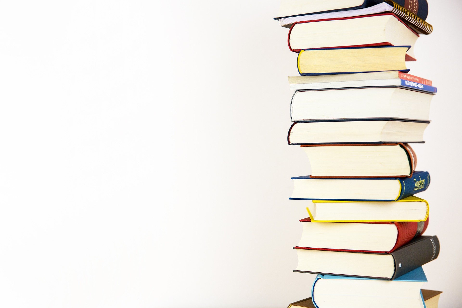 a stack of books against a white wall illustrates an enticing portfolio should you need to hire a freelance writer